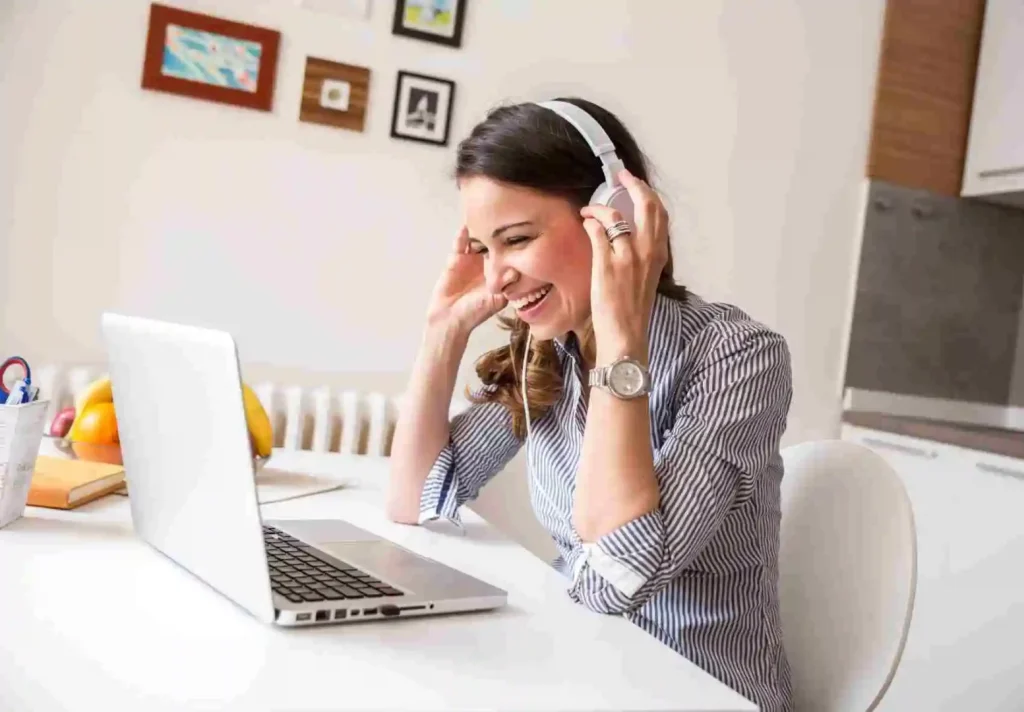 Une femme souriante portant un casque audio suit une formation d’anglais en ligne sur son ordinateur portable, avec le logo CPF visible à l’écran.